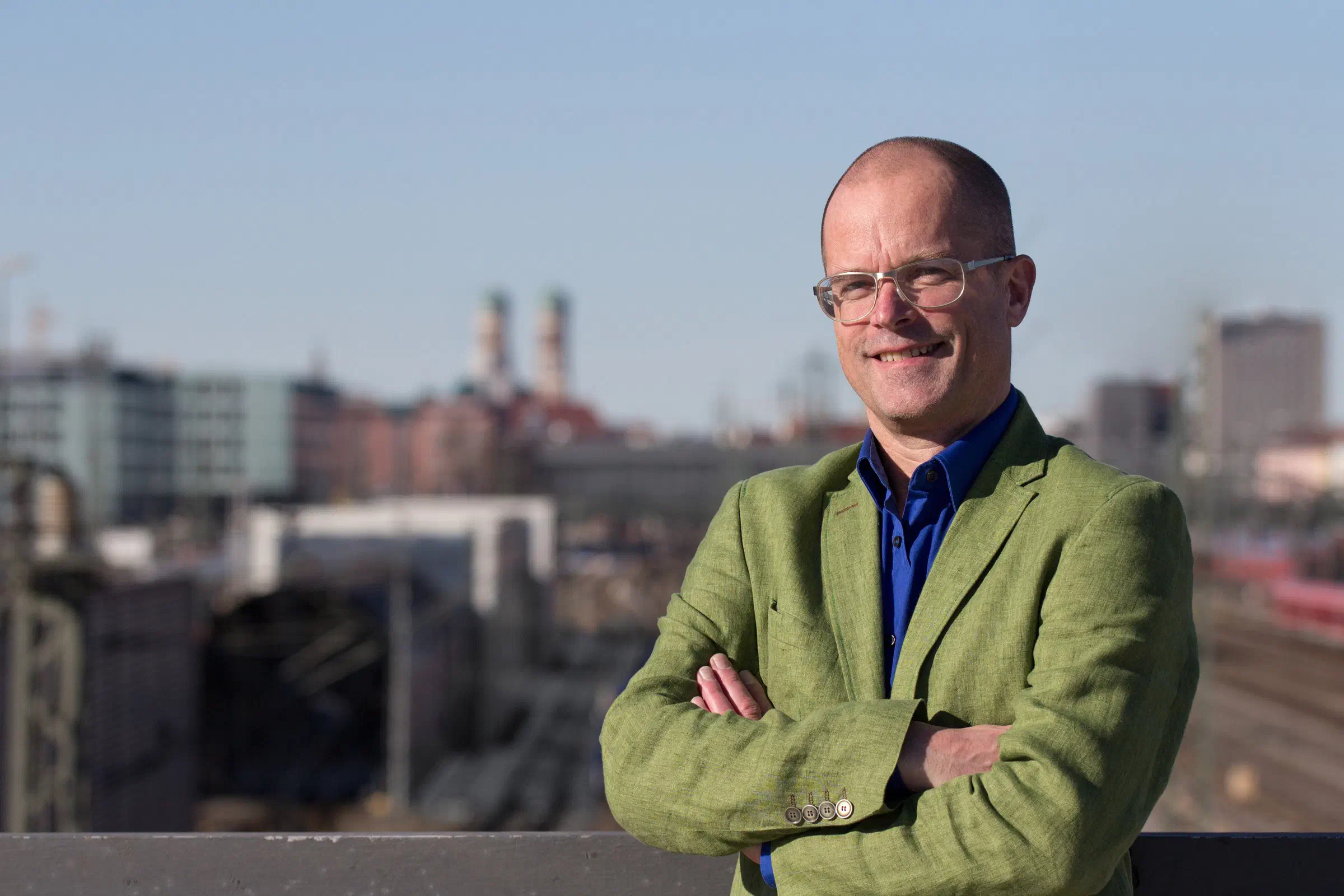 Richard Ebert mit verschränkten Armen auf der Donnersbergerbrücke, hinter ihm München mit der Frauenkirche